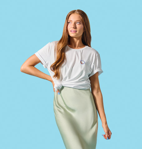 A woman wearing a Vita Coco Coconut Crewneck Tee, a wardrobe staple that pairs perfectly with her vibrant green skirt.