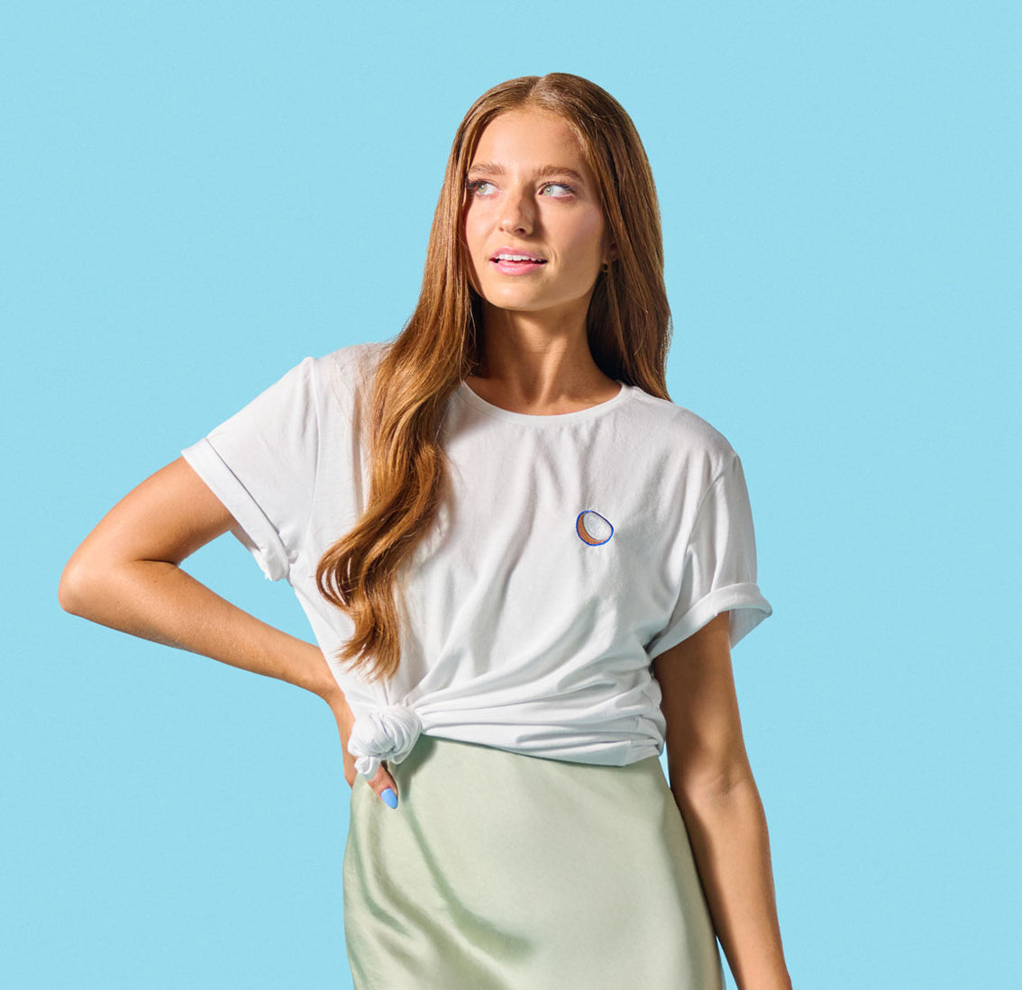 An Embroidered Coconut Crewneck Tee paired with a green skirt creates a stylish and versatile wardrobe staple for women who appreciate Vita Coco's coconut goodness.