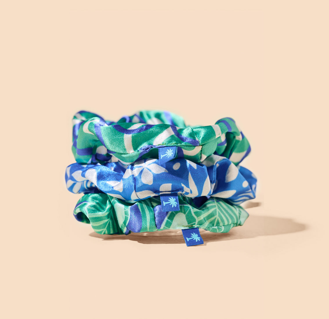 Three Vita Coco scrunchies with blue and green prints perfect for hair.